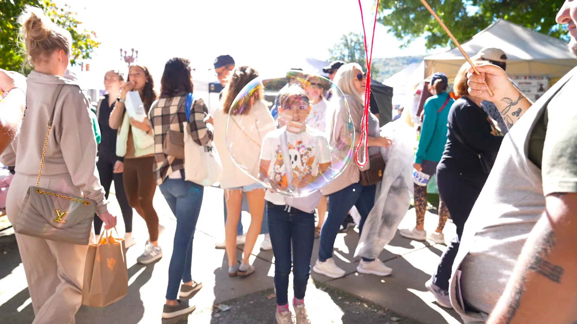 A youth Applefest attendee looks through a bubble with amazement